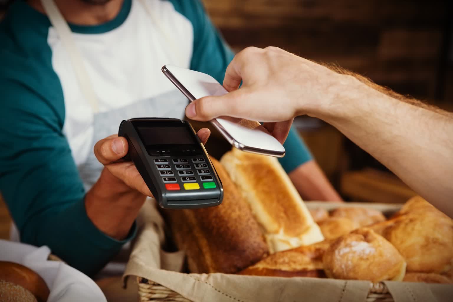 Program Polska Bezgotówkowa – dlaczego warto? 2 Klient w piekarni przykładający telefon do terminala